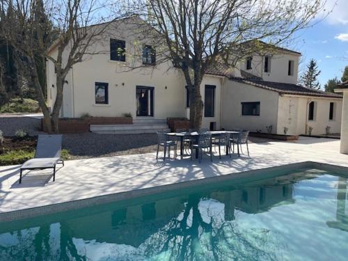 une maison avec une table et des chaises à côté d'une piscine dans l'établissement Mas Béla Vinha, piscine chauffée, mer à 30 min, à Saint-Pargoire