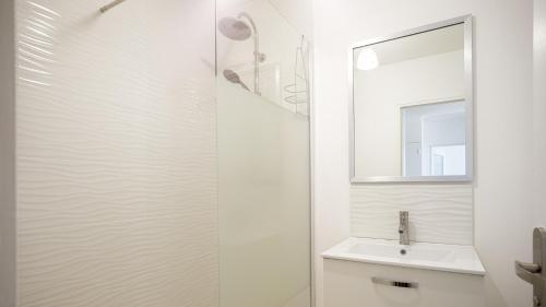 une salle de bain blanche avec un lavabo et un miroir dans l'établissement Guadariege - Proche Hypercentre - 4 personnes, à Troyes
