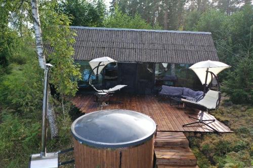 a wooden deck with a hot tub and umbrella at Black house in the forest with Hot Tube and Home theater for movies in Līči