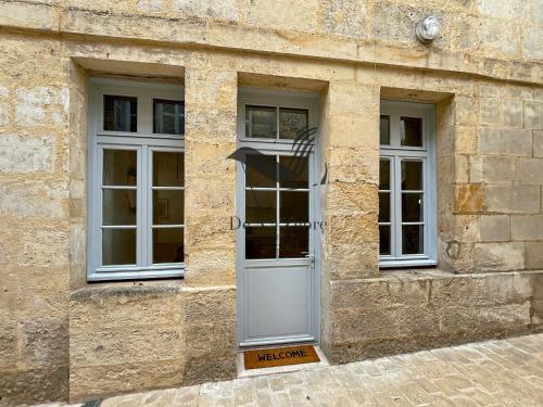 - un bâtiment en pierre avec une porte et 2 fenêtres dans l'établissement L'Escale d'Audry - Appartement avec cour situé en plein coeur de ville, à Rochefort