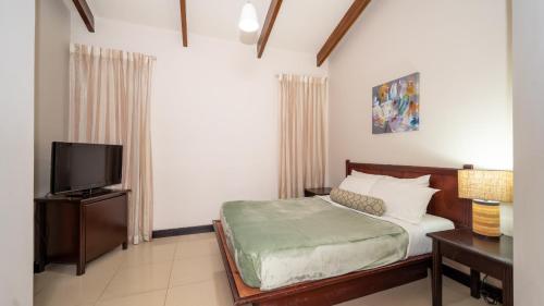 a bedroom with a bed and a flat screen tv at MonteMar Beach Condo At Playa hermosa in Sardinal