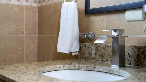 a bathroom sink with a white towel on a wall at MonteMar Beach Condo At Playa hermosa in Sardinal