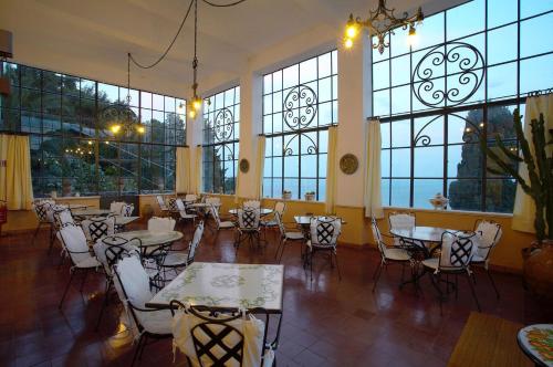 a restaurant with tables and chairs and large windows at Hotel Bel Soggiorno in Taormina