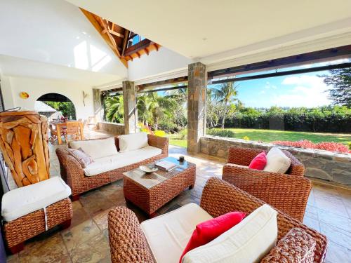 a living room with wicker furniture and a large window at Villa Ayapana in Le Morne