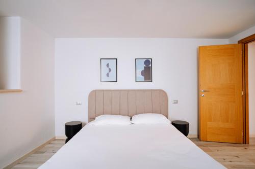 アオスタにあるAosta Holiday Apartments - Piazza Chanouxのベッドルーム1室(白い大型ベッド1台、木製のドア付)