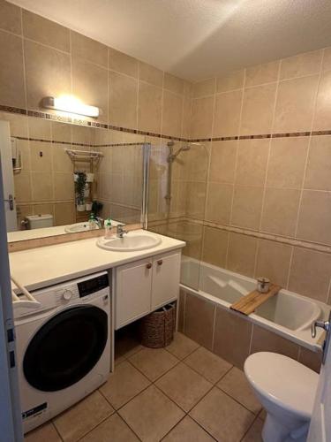 une salle de bain avec un lavabo et une machine à laver dans l'établissement L ECUME- Grand T4 duplex avec terrasses - Piscine - Parking, à Saint-Cyprien