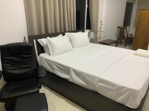 a bedroom with a white bed and a chair at Galkaduwa360 Villa in Kandy