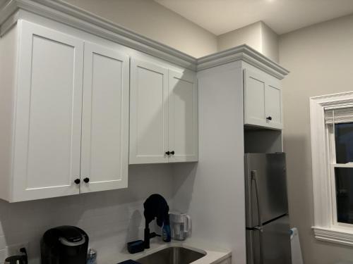 a kitchen with white cabinets and a cat on the counter at HomeStay B&B in Boston - 3 locations in Dorchester in Boston