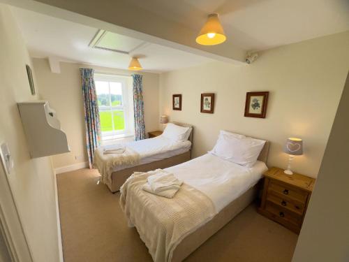 a bedroom with two beds and a window at Kirk House Longtown in Longtown