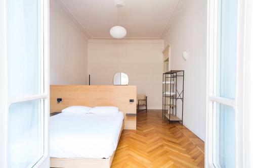 a bedroom with a white bed and a wooden floor at Aosta Holiday Apartments - Conseil des Commis in Aosta