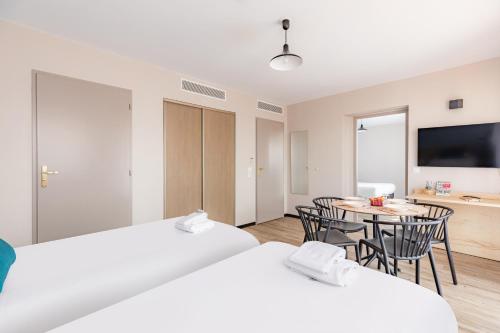 a room with two beds and a table with chairs at Appart'City Classic Montelimar in Montélimar