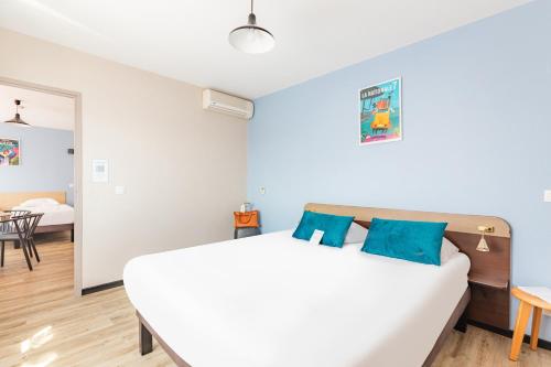 a bedroom with a white bed with blue pillows at Appart'City Classic Montelimar in Montélimar