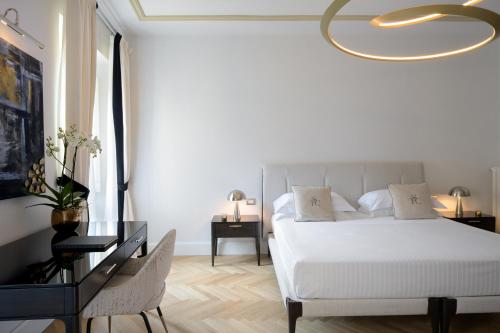 a bedroom with a white bed with a gold chandelier at Tornabuoni Suites Collection Residenza D'Epoca in Florence