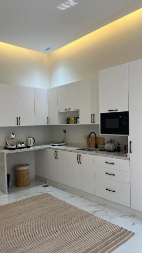 a white kitchen with white cabinets and a microwave at Dirat Al-Ghizal 1 راس الخيمة قرية اذن in Gragrah