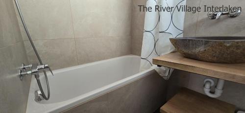 a bathroom with a sink and a bath tub at The River Village in Interlaken