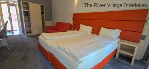 a bedroom with a large bed with an orange headboard at The River Village in Interlaken