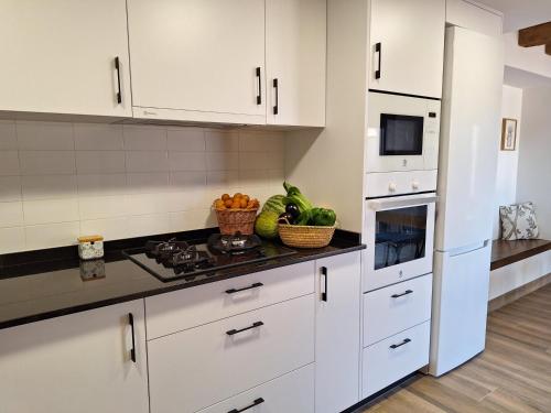 a kitchen with white cabinets and a stove top oven at La Palmera Casa Rural in L'Aldea