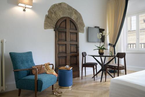 a room with a door and a chair and a table at Tornabuoni Suites Collection Residenza D'Epoca in Florence