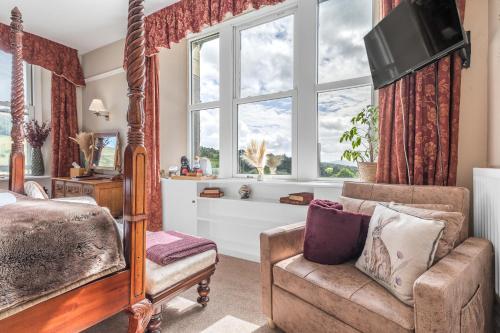 a bedroom with a bed and a chair and a television at The Mortal Man Inn in Troutbeck