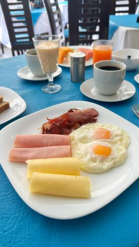 a plate of food with eggs bacon and cheese on a table at Delfines Apart Hotel in La Paz