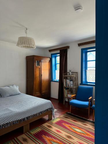 a bedroom with a bed and a chair and windows at Бабусина хатка in Leplyavo