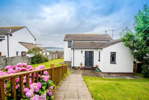a white house with a wooden fence and flowers at PuffinPatch - Beachside Cottage in Broad Haven