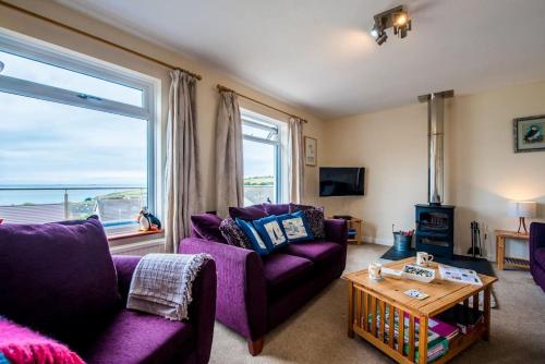 a living room with purple furniture and a large window at PuffinPatch - Beachside Cottage in Broad Haven