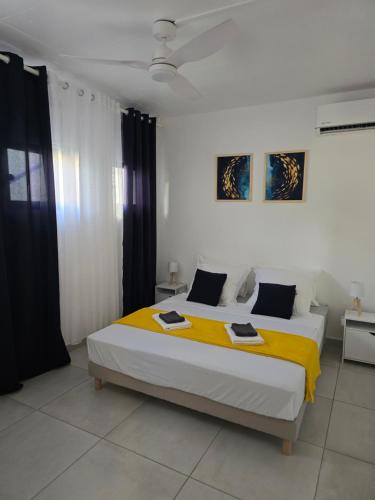 a bedroom with a large bed with a yellow blanket at Les Terrasses de la Wallon Cannelle in Les Trois-Îlets