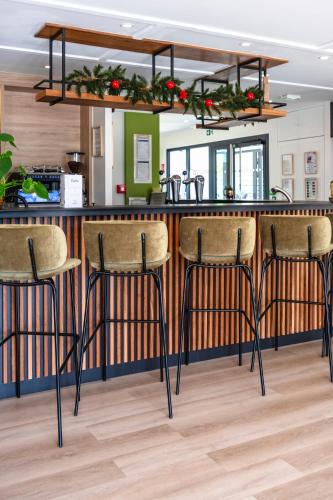 a kitchen with a bar with three bar stools at Campanile Metz Sud Jouy-Aux-Arches A31 Carrefour de l'Europe in Jouy-aux-Arches