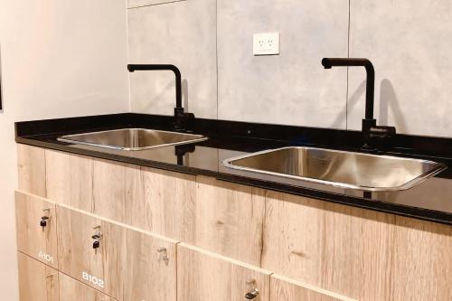 Dos fregaderos en una cocina con gabinetes de madera. en Smart AirLoft - Salta, en Salta