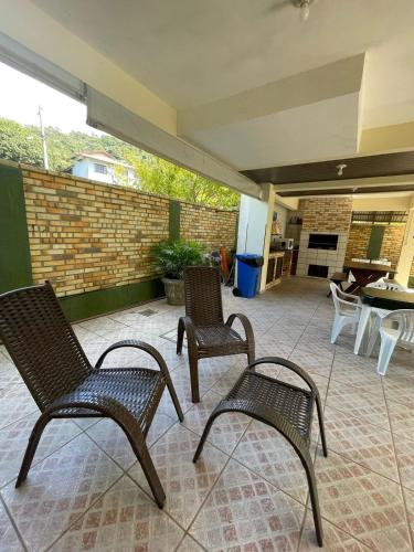 three chairs sitting on a patio with a fireplace at Pousada Ramo de Acácia in Bombinhas