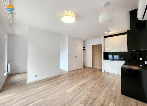an empty kitchen and living room with wooden floors at Sztutowo Perła Mierzei by Grand Apartments in Sztutowo
