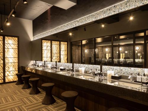 a bar with a row of sinks and stools at Kurashiki Station Hotel in Kurashiki