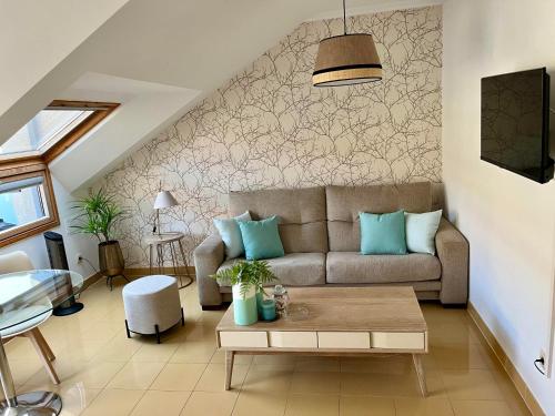 una sala de estar con un sofá y una mesa en Precioso ático con amplia terraza, en Portonovo