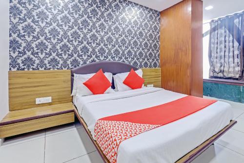 a bedroom with a bed with red pillows at Hotel New Shiv INN in Vadodara