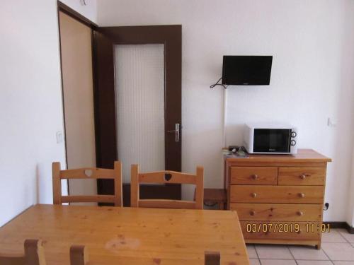 une salle à manger avec une table et une télévision sur une commode dans l'établissement Studio 4 personnes, à Briançon