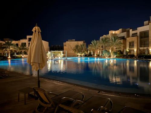 a swimming pool at night with chairs and an umbrella at Luxurious private Getaway in Mangroovy in Hurghada