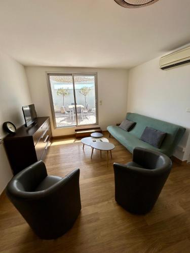 un salon avec un canapé vert et des chaises dans l'établissement Marina Régates, au Grau-du-Roi