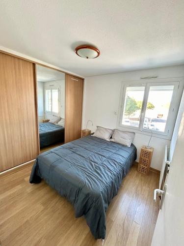 une chambre avec un grand lit avec une couverture bleue dans l'établissement Marina Régates, au Grau-du-Roi