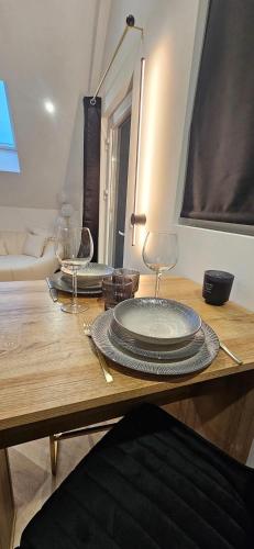 - une table en bois avec 2 assiettes et des verres à vin dans l'établissement Black Romance, à Yville-sur-Seine