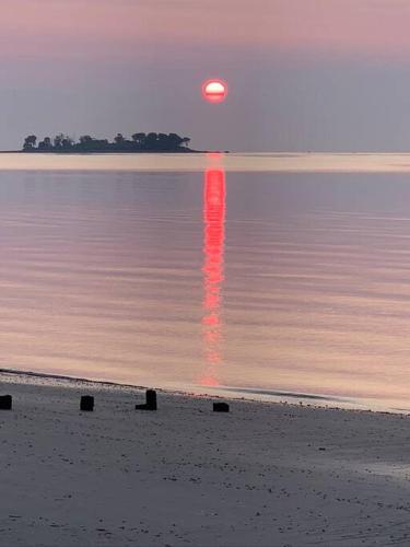 a sunset on the beach with the sun reflecting in the water at Pet Friendly Milford Beachfront Home in Stratford