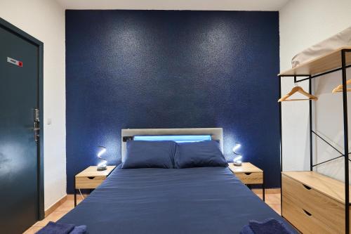 una camera da letto con un letto e una parete blu di Le Cabrit - Climatisation - Wifi a Perpignano