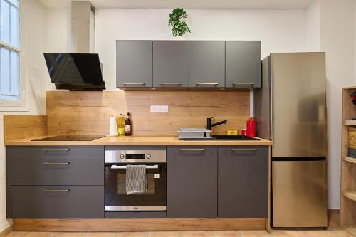 une cuisine avec une cuisinière et un réfrigérateur dans l'établissement Le Cabrit - Climatisation - Wifi, à Perpignan