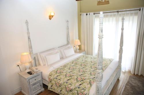 a bedroom with a bed and a phone on a table at Pedro Barn Hotel at Little England Cottages in Nuwara Eliya