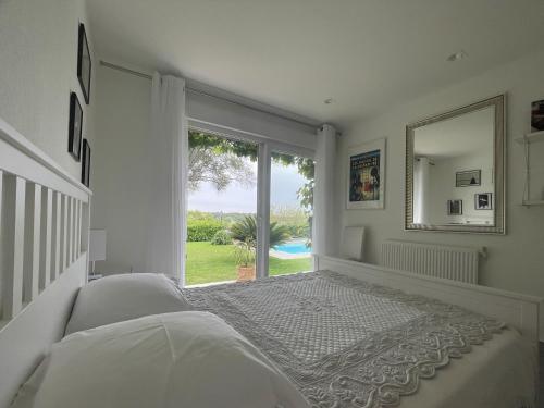 une chambre blanche avec un lit et une grande fenêtre dans l'établissement Belle villa calme, piscine, 4 chambres climatisées à 8km de Montpellier classée meublé de tourisme 4 étoiles, à Saint-Gély-du-Fesc