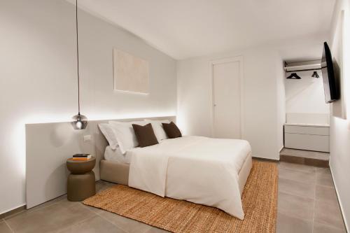 a white bedroom with a white bed and a rug at Cali Suites Mergellina in Naples