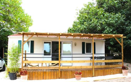 une petite maison avec une terrasse couverte et une clôture dans l'établissement Le Petit Saint Trophime, à Saint-Rémy-de-Provence