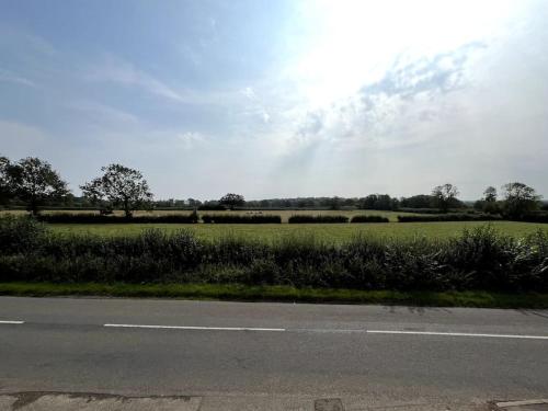 an empty road next to a field of grass at Fern Cottage in Brinklow