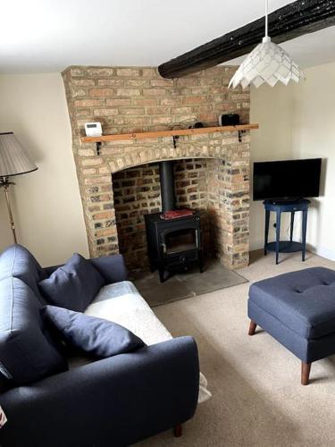 a living room with a couch and a brick fireplace at Fern Cottage in Brinklow