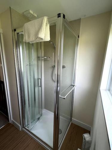 a shower with a glass door in a bathroom at Fern Cottage in Brinklow